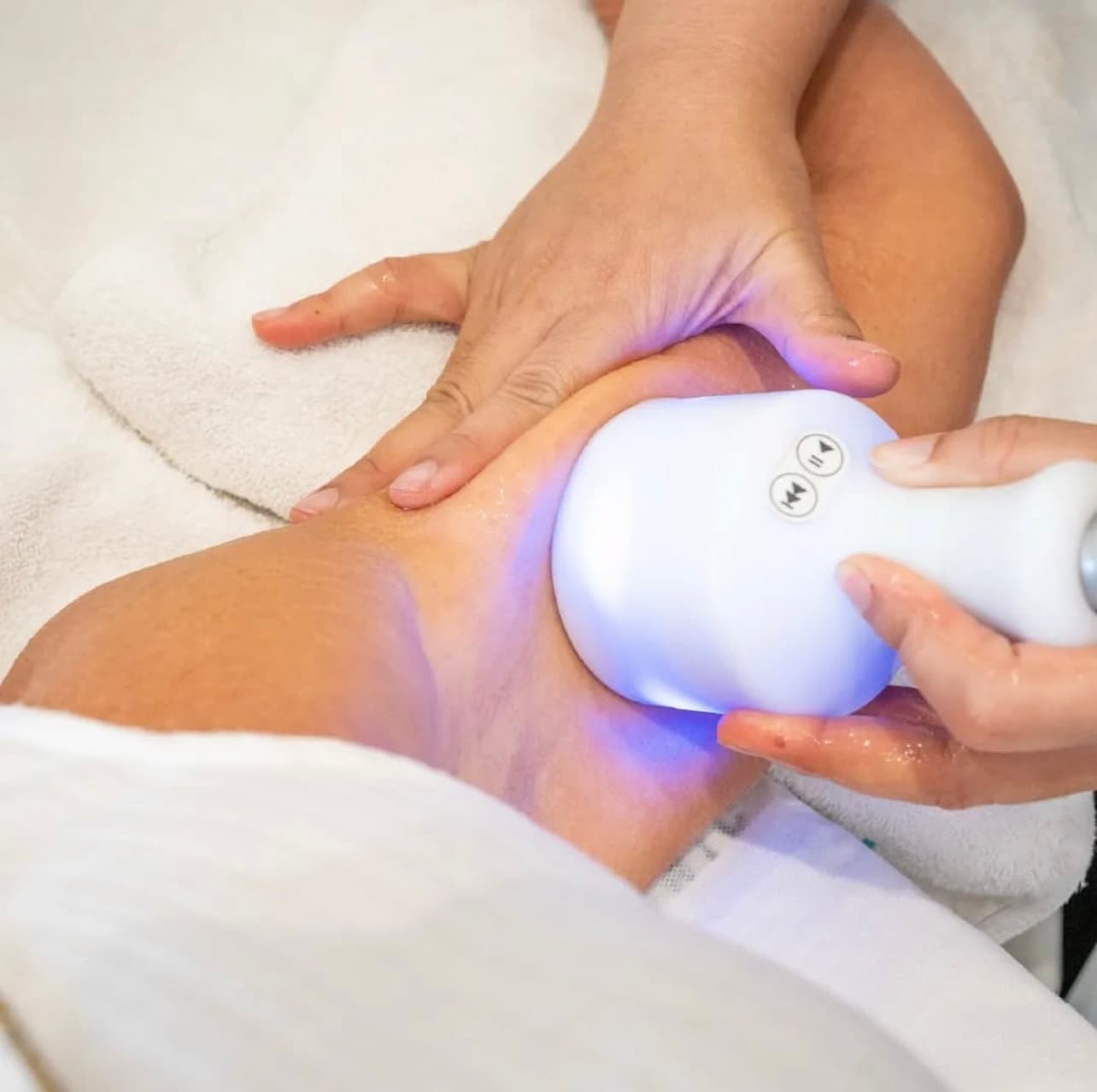 Cryoskin treatment in action with practitioner applying blue-lit cryotherapy handpiece to client body, conveying professional care and advanced technology