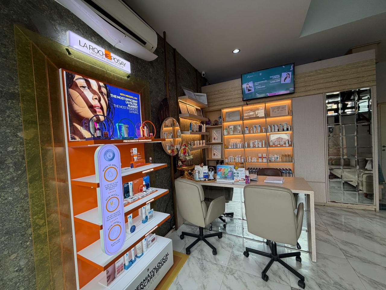 Interior consultation area with La Roche-Posay product display, backlit skincare shelving, consultation desk with cream-colored chairs, and marble flooring.