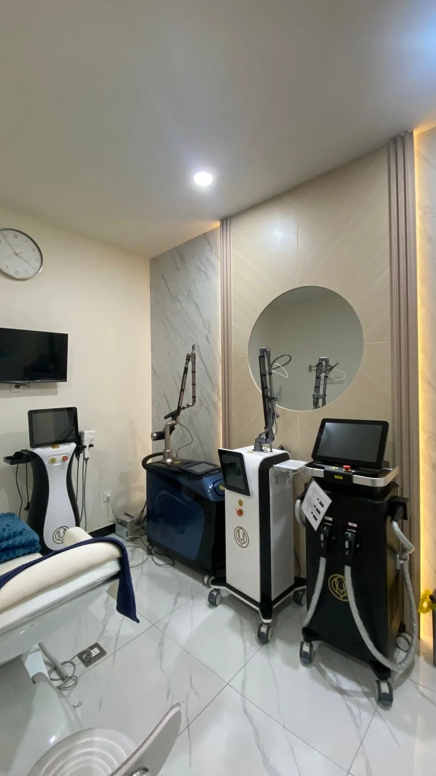 Clean waiting area with marble accent wall featuring the clinic's gold signage, blue and beige seating, and a small coffee table in a modern minimalist setting.