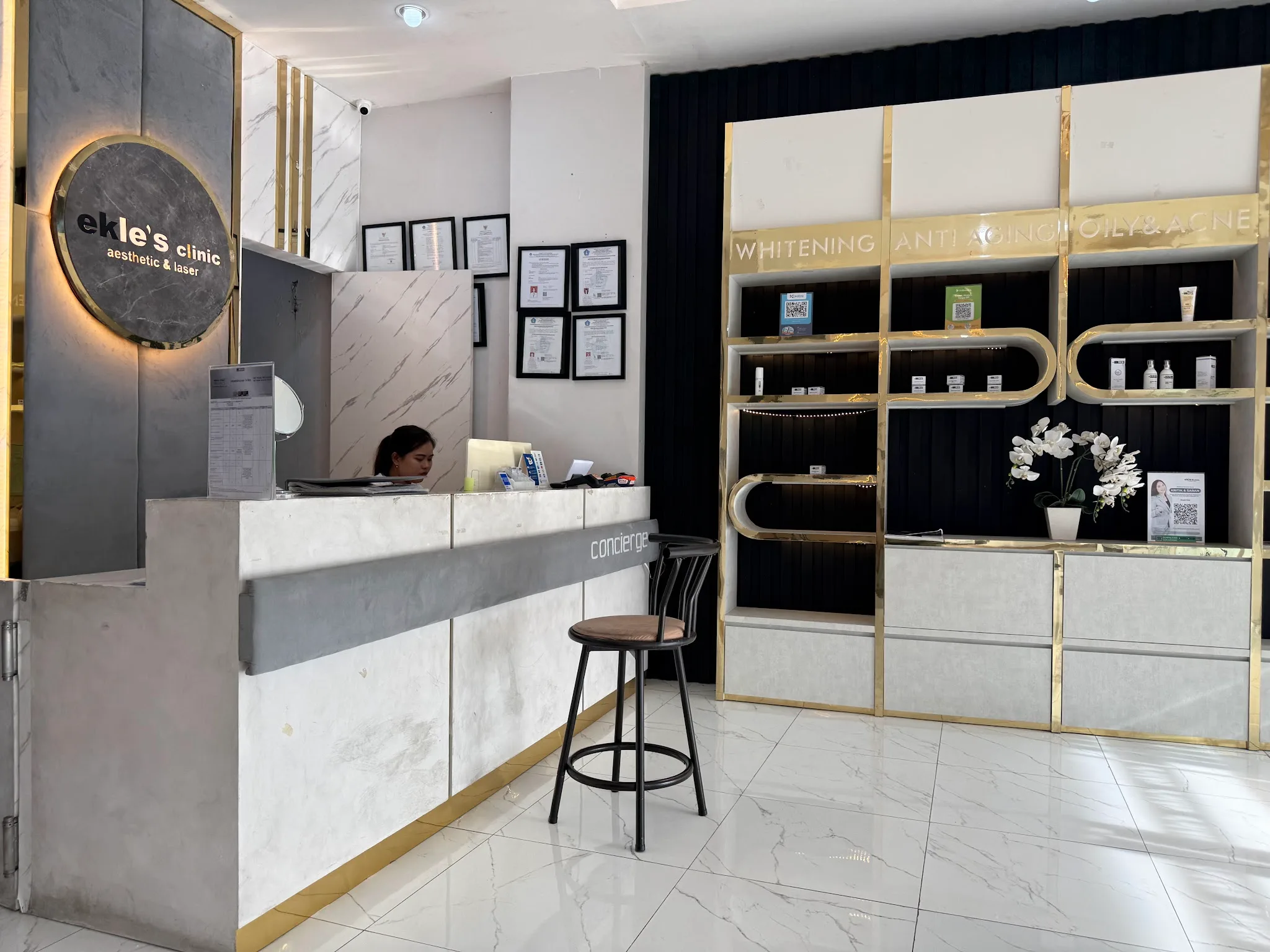 Receptionist behind wooden front desk with promotional materials and Independence Day decorations. Cluttered, reduces premium feel.