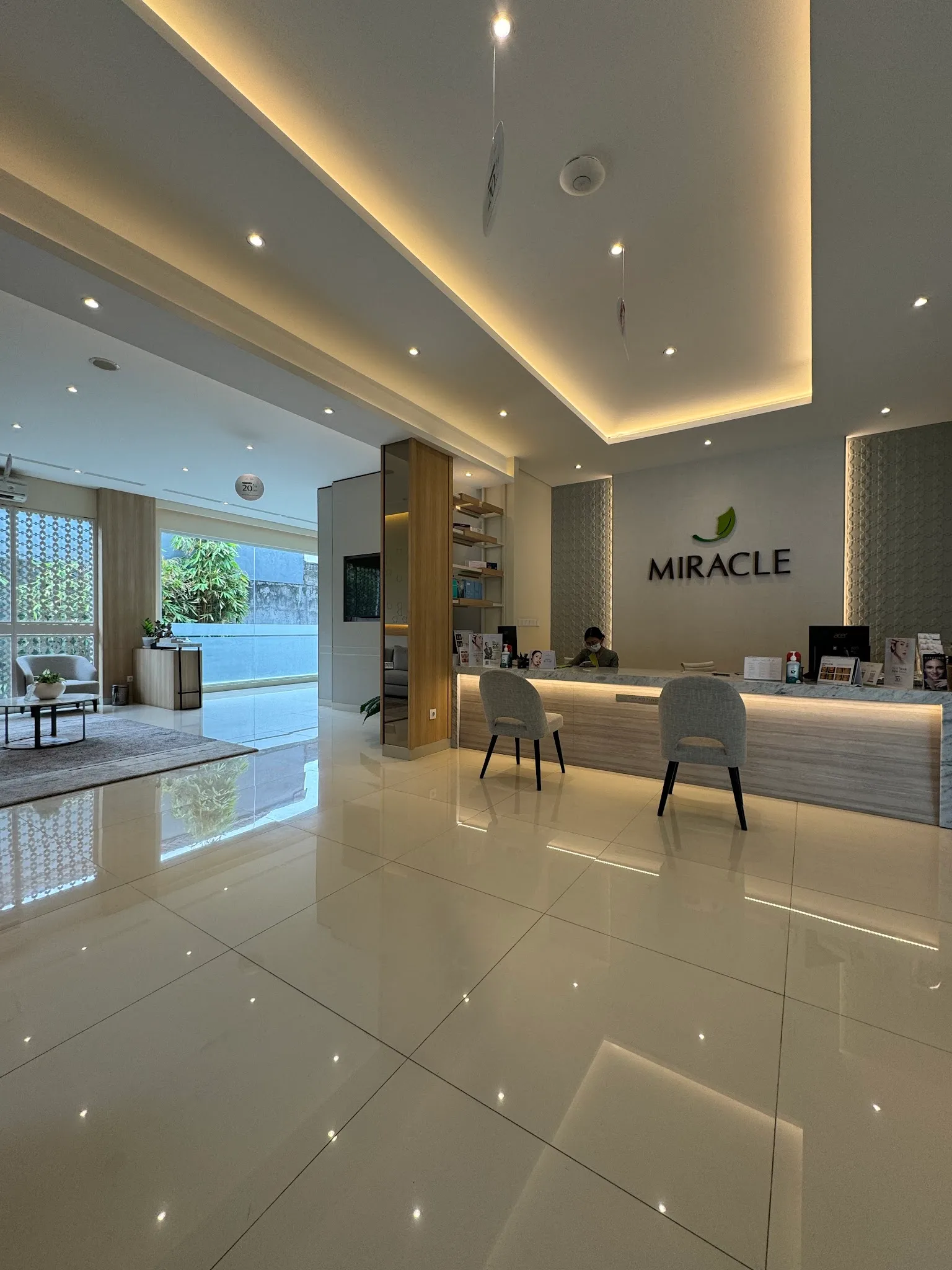 Spacious clinic interior with polished floors and glass entrance featuring the clinic logo, but cluttered with multiple promotional banners and discount signs.