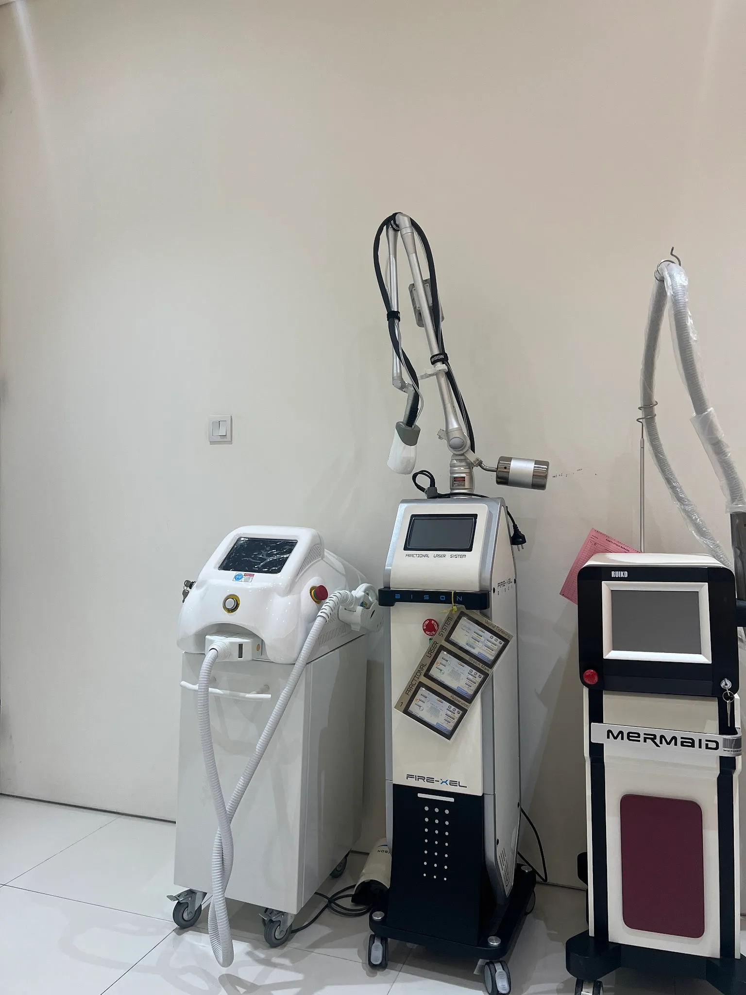 Low-angle shot of a fractional laser system and other equipment in a treatment room, but the awkward perspective and lens flare reduce its quality significantly.